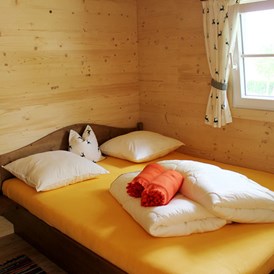 Glampingunterkunft: Ferienhütte "Drachenwand": Schlafzimmer mit Doppelbett - Ferienhütten am CAMP MondSeeLand