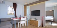 Luxuscamping - getrennte Schlafbereiche - Wohnzimmer mit Esstisch und Stühlen
 - Mobilheime Typ C auf Camping Cikat