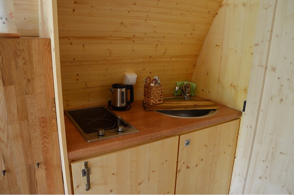 Glampingunterkunft: Küche mit Kochplatten, Spüle und Kühlschrank mit Eisfach - Glamping-Pod Waldemar am Wurlsee - Naturcampingpark Rehberge