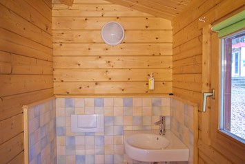 Glampingunterkunft: Bad mit Waschbecken und WC - Ferienhaus Rosalie am Wurlsee - Naturcampingpark Rehberge