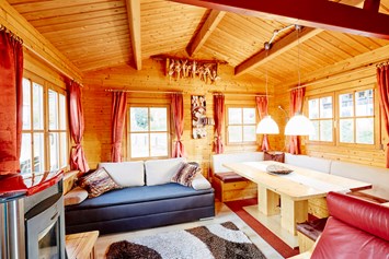 Glampingunterkunft: Wohnbereich mit gemütlicher Sitzecke Pelletsofen, ausziehbarer Couch - Blockhütte Tirol Camping Dreiländereck Tirol