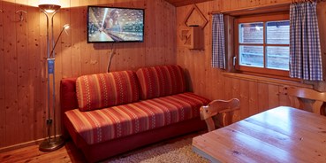 Luxuscamping - Umgebungsschwerpunkt: Berg - ausziehbare Couch, gemütlicher Ess- Sitzbereich - Kleine Blockhütte Camping Dreiländereck Tirol
