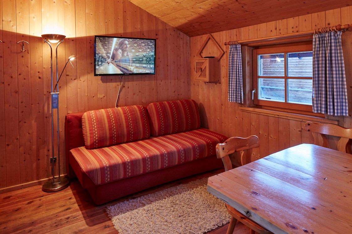 Glampingunterkunft: ausziehbare Couch, gemütlicher Ess- Sitzbereich - Kleine Blockhütte Camping Dreiländereck Tirol