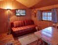 Glampingunterkunft: ausziehbare Couch, gemütlicher Ess- Sitzbereich - Kleine Blockhütte Camping Dreiländereck Tirol