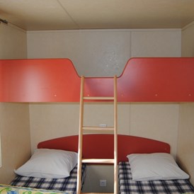 Glampingunterkunft: Kinderslaapkamer met 2 eenpersoonsbedden, een hoogbed en een ingebouwd babybed - Luxus Mobilheime Foxhouse für 6 Personen auf Camping Fuussekaul