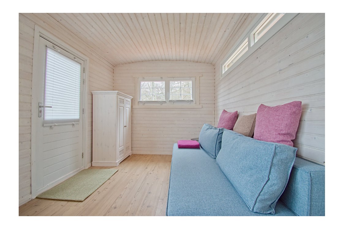 Glampingunterkunft: gemütliches Schlafsofa und Kleiderschrank - Tiny House am See - Naturcampingpark Rehberge